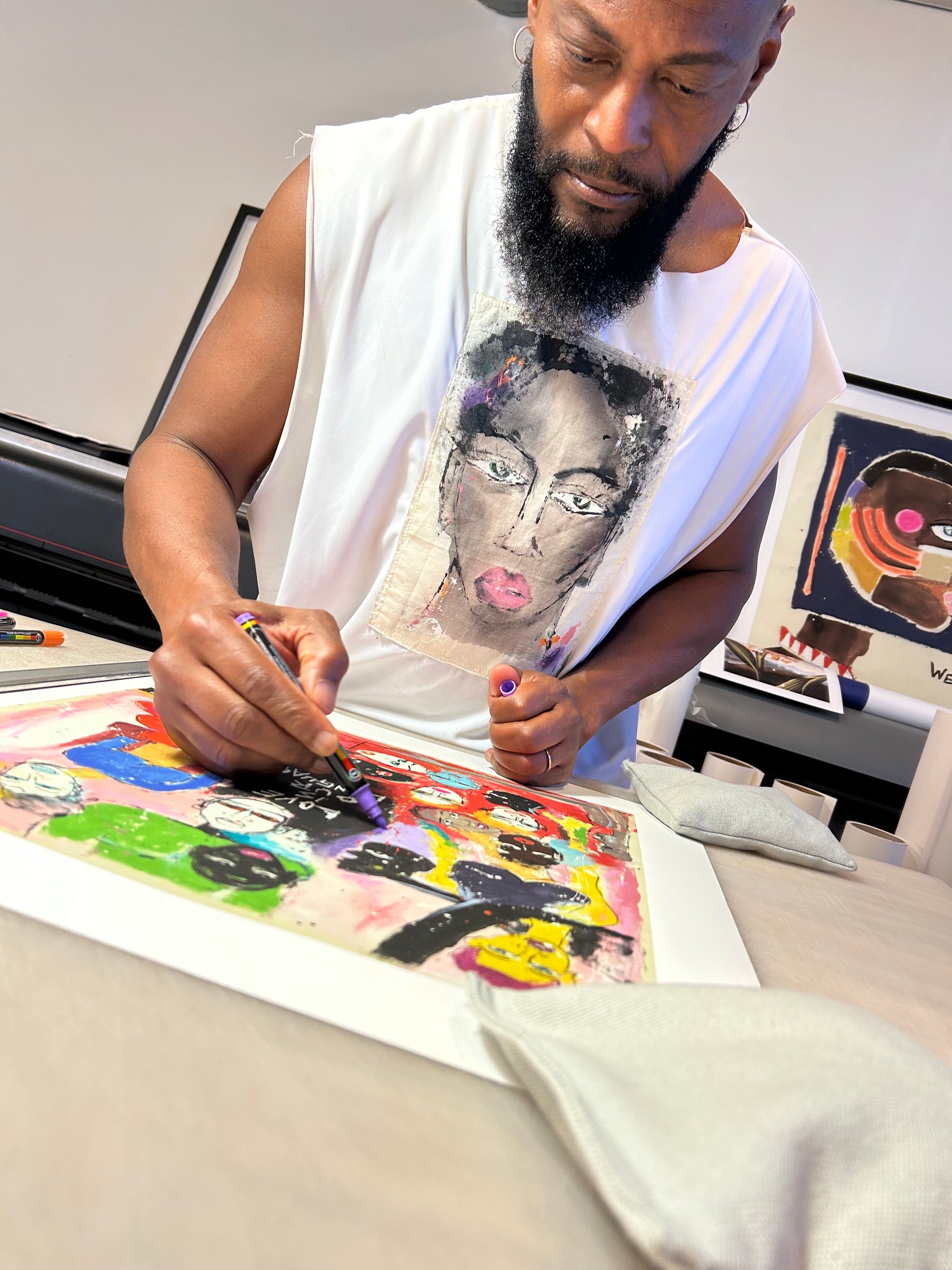 Miles Regis, a Black male artist, hand embellishing his print, 'Love Is Our Language' at a work table.
