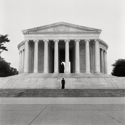 “Jefferson Memorial” by Carrie Mae Weems, black and white print of the Jefferson Memorial in Washington, D.C. Features a dark figure in a long black dress standing on the steps, facing the statue of Thomas Jefferson. Displays the tall columns and a triangular pediment of the Jefferson Memorial. 